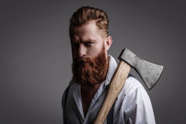 Sakallı adam gri yolda izole edilmiş. Sakallı adam, baltayı tut. Saç ve sakal bakımı. Yakışıklı, sakallı, vahşi adam. Sakal şekillendirme. Bıyıklı, Kafkas bir hippi. Erkeklik algısı.