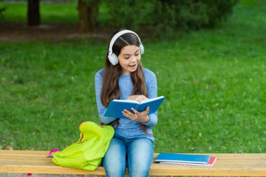 Kızım sesli kitap dinle ve kitap oku. Audiobook kitaba karşı. Öğrenci kız. Okul eğitimi. Liseli kız dışarıda kitap okur ve sesli kitap dinler. Okula dönelim. Eğitim ve bilgi. Merak ediyorum..