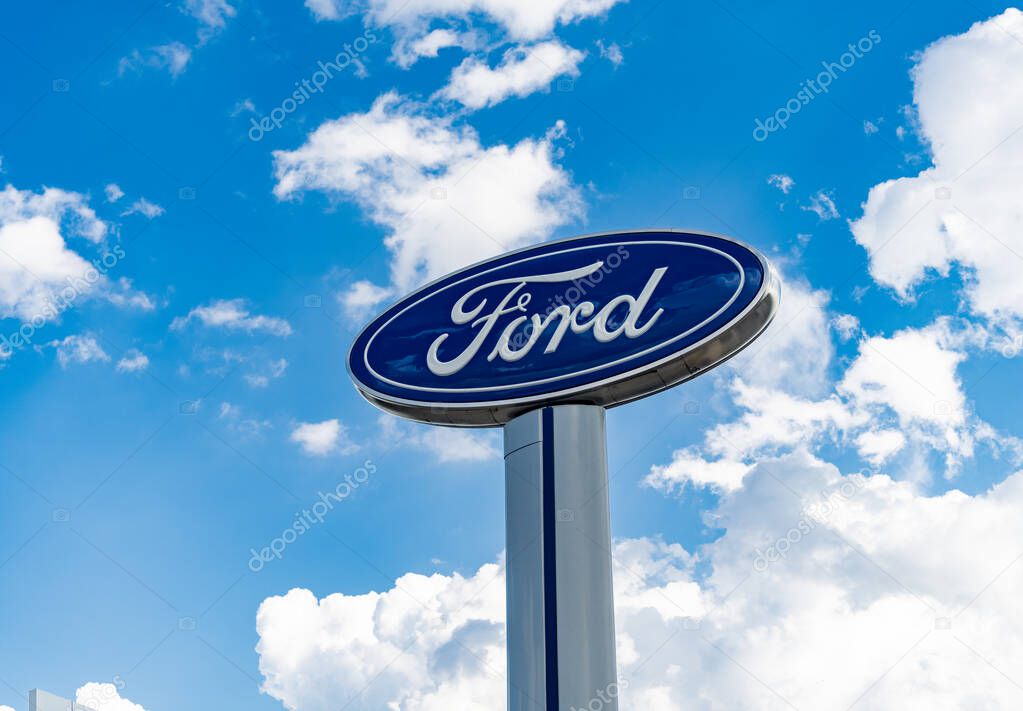 Chicago, USA - August 17, 2024: Ford logo sign against blue cloudy sky. Ford motor company is a oldest car company. Ford sign near dealership