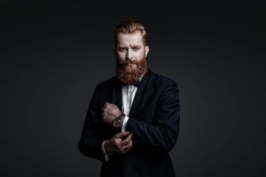 Erkek aksesuarı. Smokinli beyefendinin lüks bir saati var. Pahalı bir kol saati. Smokinli papyonlu adam ve saat. Zarif saat aksesuarı. Zaman doldu. Gri renkte soyutlanmış zarif beyefendi..