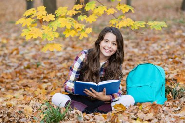 Sonbahar kitabı. Okula dönelim. Okul eğitimi. Dışarıda kitap okuyan liseli kız. Genç kız sonbahar parkında kitap okuyor. Eğitim ve bilgi. Bilgi toplama günü. Kendi kendine eğitim. Zeki üniversite öğrencisi..