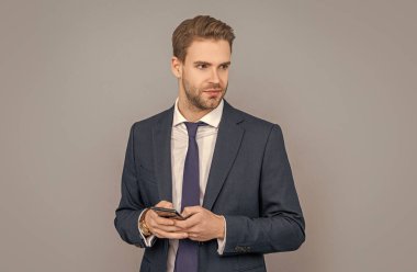 Telefon kullanan bir iş adamı. Stüdyoda erkek telefonu konuşması. Telefonu olan genç bir iş adamı. İş iletişimi. Gri yolda izole bir şekilde telefonda sohbet eden sıradan bir iş adamı. sesli mesaj bırakarak.