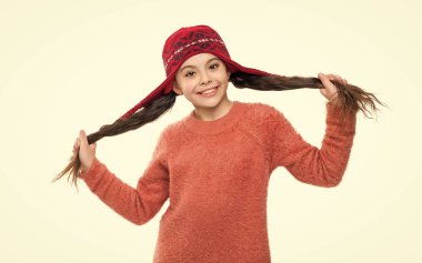 Sıcak kış şapkası takan genç çocuk portresi. Kız çocuğu beyazda izole edilmiş. Mutlu bir çocukluk. Örgü süveter giyen genç bir kız. Kış modası. Kış şapkalı şık kız. Sıcak kış giysisi.