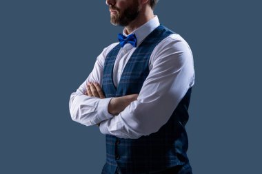 Smokin giymiş şık bir beyefendi. Yeleği ve zarif papyonu var. Gri üzerine izole edilmiş resmi bir etkinlikte..