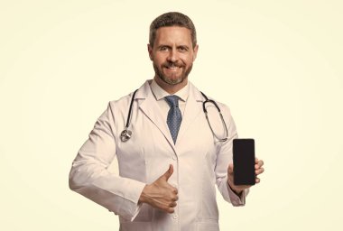 Tıbbi başvuru. Mutlu doktor tıbbi telefon uygulamasını sunar. Telefonunda ilaç var. başparmak yukarı.