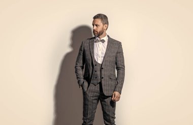 Smokin giyen yakışıklı adamın fotoğrafı. Adam smokin resmi takım elbise giyiyor. Gri arka planda smokinli adam. Stüdyodaki smokin giyen adam..