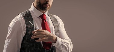 man barbering in barbershop studio, cropped view. bearded man at barbershop. unshaven man hold scissors in barbershop isolated on grey background. man cut hair with barbershop scissors.