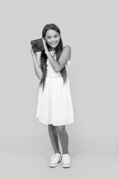 stock image glad teen girl hold present box on yellow background.