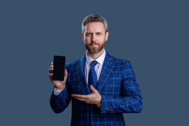 Ürünü sunuyorum. İş uygulamasının reklamı. İspanyol iş adamı telefon ekranını sunuyor. Griler 'de izole edilmiş bir telefon gösteren bir iş adamı. Takım elbiseli adam. Yeni telefon uygulaması.