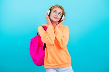 Genç bir kız mavi üzerine izole edilmiş. 1 Eylül. Üniversitede eğitim. Öğrenci kız okul çantasını tutuyor. Okula dönelim. Bilgi toplama günü. Bilgi ve eğitim. Öğrenci hayatı. Müzik dinle..