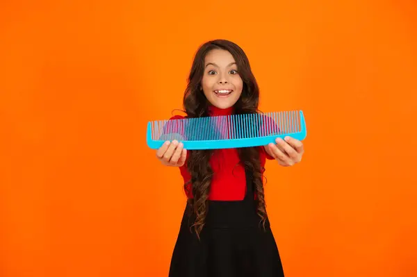 stock image Haircare and hair loss. Girl use hair comb. Comb and hairbrush. Teen girl combing curly hair. Hairdresser. Girl with hairbrush isolated on orange. Teen beauty hairstyle. Beauty salon.