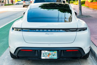 Miami Beach, Florida USA - 9 Haziran 2024 Miami plajında Porsche Taycan beyaz rengi. Ocean 'daki lüks araba porshche' si Miami plajına gidiyor. ön köşe görünümü