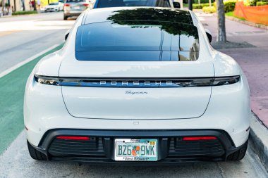 Miami Beach, Florida USA - June 9, 2024: Porsche Taycan white color at miami beach. luxury car porshche at ocean drive Miami beach. front corner view clipart