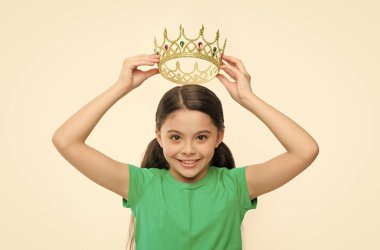 Prenses gibi davranmak iştir. Çocuk prensesin altın taç sembolünü takıyor. Tatlı kız taç takıyor. Çocukluk konsepti. Prenses olmayı hayal eden her kız. Küçük hanım prenses. Kraliyet ailesi.