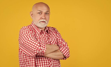 Sarı arka planda damalı gömlekli yaşlı adam ya da büyükbaba hayrete düştü..