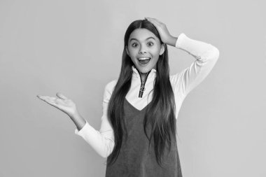 Sarı arka planda uzun saçlı şok bir çocuk. ürün sunuluyor.