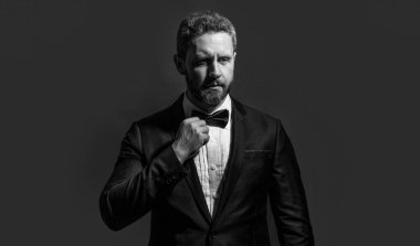 Karizmatik bir adam smokin giyer. Formalite icabı smokinli adam kırmızı arka planda izole edilmiş. Stüdyoda resmi kıyafet. Resmi kıyafet giyen adamın fotoğrafı..