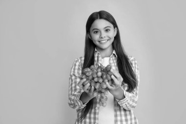Sarı arka planda taze üzümlü mutlu çocuk. vitaminler.