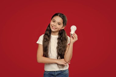 photo of cheerful teen innovation girl with bulb. teen innovation girl isolated on red. teen innovation girl in studio. teen innovation girl on background.