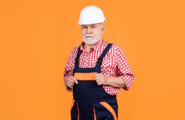Sarı arka planda miğferli kıdemli bir inşaatçı..