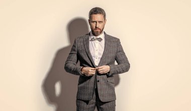 Karizmatik adam smokin giyer. Gri arka planda smokinli adam. Stüdyodaki smokinli adam. Smokin giyen adamın fotoğrafı..