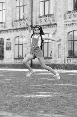 surprised denim girl with backpack jumping outdoor.