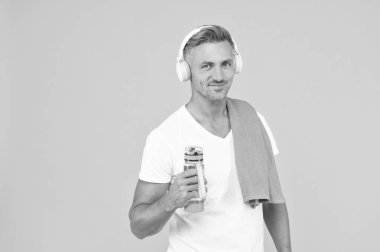 Mutlu adam şişeyi sağlıklı bir yaşam için tutuyor. Sağlıklı yaşam tarzı için spor şişesi olan adam sarıda izole edilmiş. Spor yaşam tarzını korumak için elinde şişe tutan adam. Eğitimden sonra havluyla şişesi olan adam.