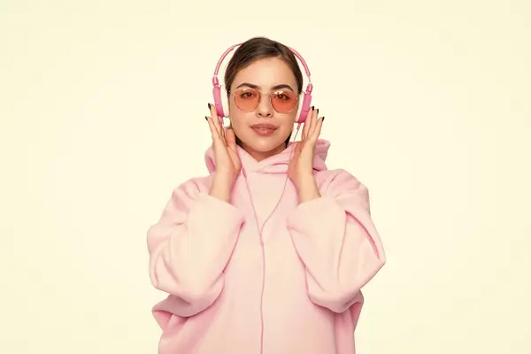 stock image Serious woman student in casual pink hoodie and glasses listening to audio course in headphones isolated on white.