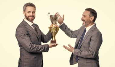 Gülümseyen iş adamları beyaz arka planda izole edilmiş ödülü kutluyorlar. İş adamları ödülü stüdyoda kutluyor. İş adamları ödülü kutluyor. İş adamlarının fotoğrafı şampiyonluk kupası ile ödülü kutluyor.