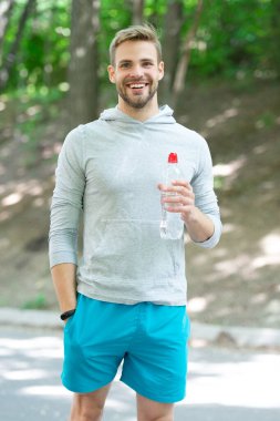 Sıvı yeterliliği. Susuz kalma. Susamış sporcu. Adam maden suyu tutuyor. Susadım. Plastik şişeli genç bir adam. Sağlıklı bir yaşam tarzı. Vücutta su dengesi. Umutsuzca bir yudum.