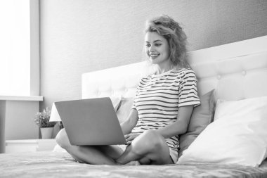 Evde dizüstü bilgisayarla çalışan pozitif kadın blogcu. Blogcu kadın evde çalışıyor. Blog yazarı için ev işi. Yatakta dizüstü bilgisayarlı bir kadın.