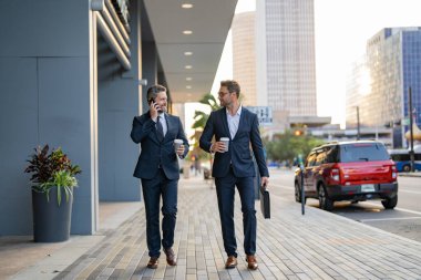 Takım elbiseli işadamları dışarıda yürüyor. Şehirde yürüyen ve konuşan iki işadamı. İş adamları konuşuyor. Yürüyen ve konuşan iki iş adamı. New York 'ta iş arkadaşı yürüyüşü. Başarı ve fırsat.