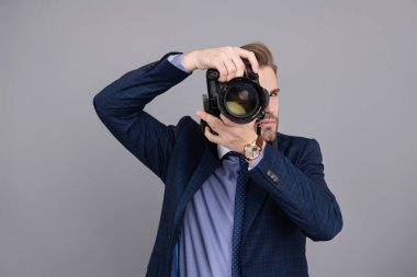 Takım elbiseli bir fotoğrafçı. Kameralı iş fotoğrafçısı. Gri renkte fotoğraf çeken gazeteci. Paparazzi fotoğrafçısı. İş adamı, fotoğraf makinesini tut. Serbest fotoğrafçı..
