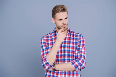 Gündelik giyinen milenyum adamı. Yakışıklı genç adam. Sıradan gömlekli bir adamın portresi. Gri üzerinde kollarını çapraz tutuyor. Tıraşsız erkek derisi. Erkek güzelliği ve saç stili. Erkek saç kesimi.