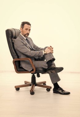 Profesyonel lider CEO. Ofis koltuğundaki iş adamı. Takım elbiseli adam liderliği temsil ediyor. İş liderliği ve başarı. İş adamı lideri ofis koltuğunda oturur. İş başarısı. Yatırım bankacısı.