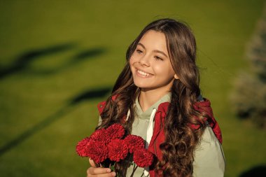 Çiçek buketi olan mutlu bir genç kız. Dışarıda çiçekli genç bir kız var. Sonbahar çiçekli genç bir kızın fotoğrafı. Sonbahar çiçekli genç kız..