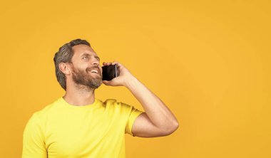 Arka planda gülümseyen adam araması, kopyalama alanı. Stüdyodaki adam aradı. Telefondaki adamın fotoğrafı. Sarı hattan izole edilmiş bir adam arıyor..