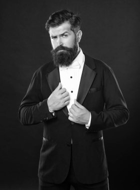 bearded man in tuxedo on black background, bow tie.