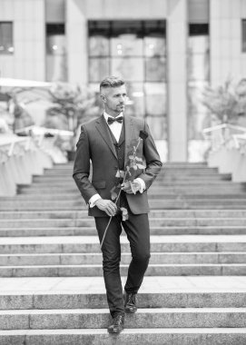 Smokinli şık bir adam. Smokin giymiş, papyonlu bir adam. Kırmızı güllü beyaz smokinli adam..