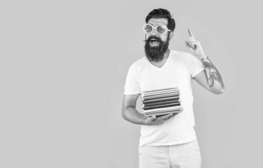 Okul için kitap yığınıyla şaşırmış bir öğrenci. Gözlüklü adam okul kitaplığını sarı arka planda izole etmiş. Erkek öğrenci bilgisi. Okula dönüyorum. Öğrenci adam bilgi alır..