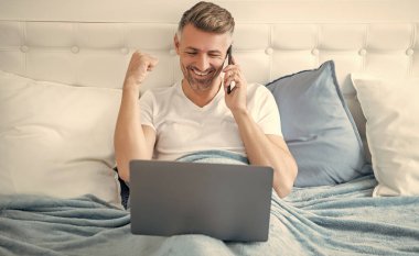 Olgun bir adamın telefonda konuşmasına ve laptopla yatakta çalışmasına sevindim..