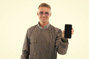 Mutlu gülümseyen iş adamı iş adamı yöneticisi beyaz iş yeri için boş cep telefonu ekran modeli gösteriyor..