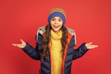 Kalın giysiler giyen çocuk portresi. Olumlu duygularını ifade et. Kış modası. Şapkalı, kıvırcık saçlı, şaşkın çocuk. Kadın manken. Paltolu genç kız..