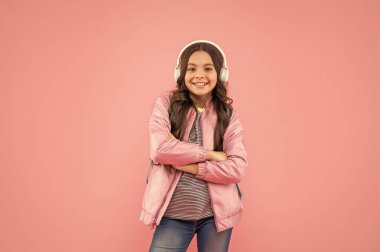 Neşeli çocuk kulaklıkla müzik dinle ve pembe arka planda sırt çantası taşı, çocukluk..