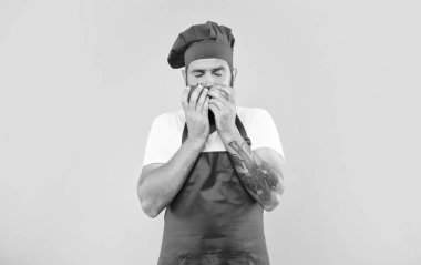 Yemek önlüğü ve domates kokulu, kapalı gözlü, sarı arka planlı, şef..