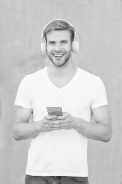 Mutlu adam mp3 müzik listesi açıyor. Adam dışarıda mp3 müzik listesi kullanıyor. Adam mp3 müzik listesini beyaz gömlek giyerek seçiyor. Man mp3 müzik listesinin kulaklıkla fotoğrafı.