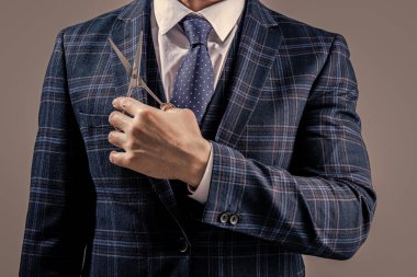 Berber adamın yakın plan çekimi gri arka planda izole edilmiş bir makas tutuyor. Makasla berber adam. Berber salonundaki makaslı adam. Berber makaslı bir adamın fotoğrafı..