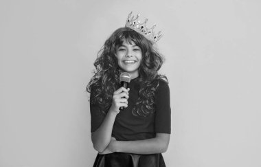 glad kid in crown with microphone on yellow background.