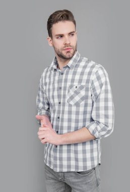 Gri arka planda kareli gömlekli genç bir adam izole edilmiş. Şık, rahat gömlekli bir adam. Stüdyoda stil sahibi bir adam. Kirli sakalı olan beyaz bir adam..