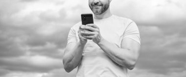 Gökyüzü arka planında akıllı telefondan konuşan bir adamın görüntüsü.